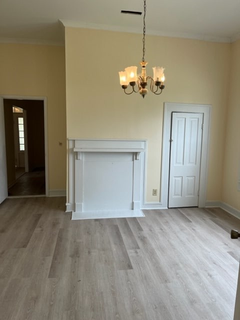 unfurnished dining area featuring light wood-style floors, baseboards, a notable chandelier, and ornamental molding