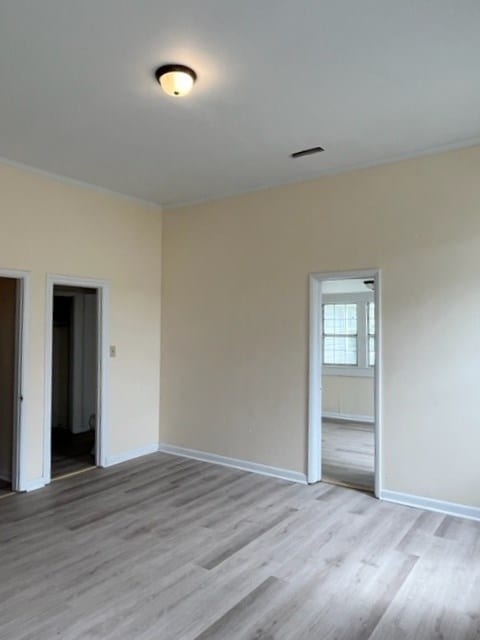 spare room featuring baseboards and light wood finished floors