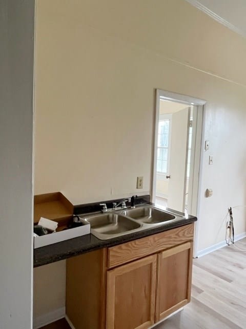 kitchen featuring dark countertops, light wood-type flooring, baseboards, and a sink