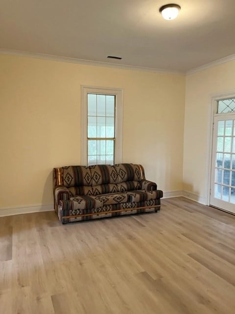 living room with baseboards, wood finished floors, and crown molding