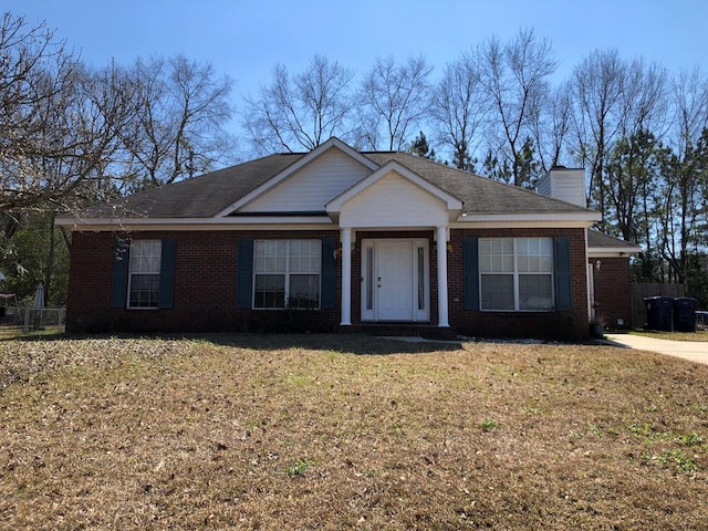 view of front facade with a front yard, brick siding, and a chimney