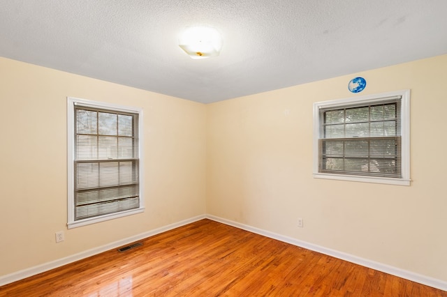 spare room with a textured ceiling and light wood-type flooring