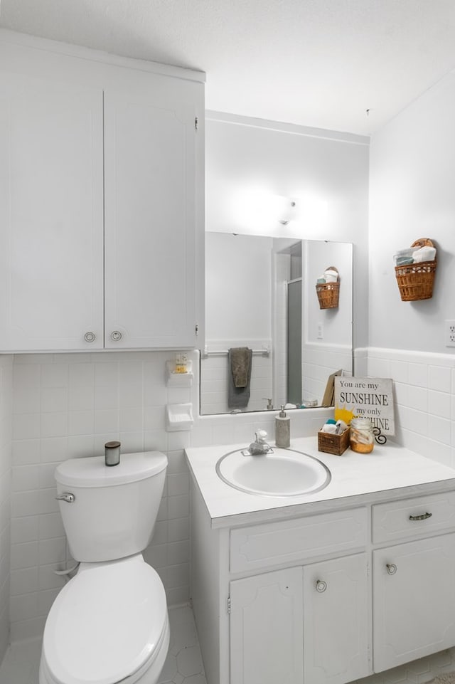 bathroom with vanity, toilet, and tile walls