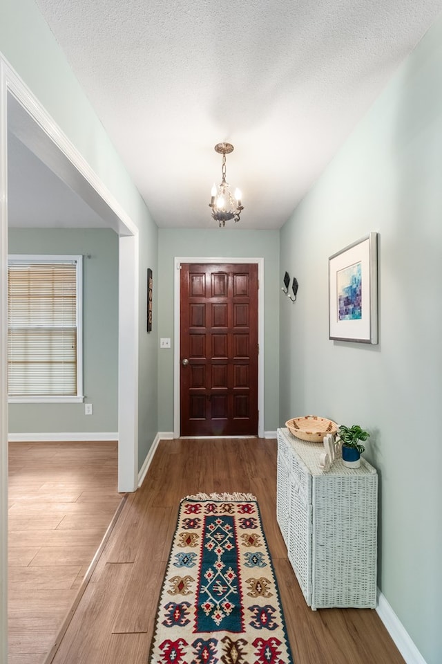 entryway featuring hardwood / wood-style floors, a textured ceiling, and a notable chandelier