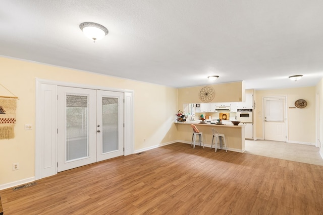 kitchen featuring kitchen peninsula, french doors, white oven, and light hardwood / wood-style flooring