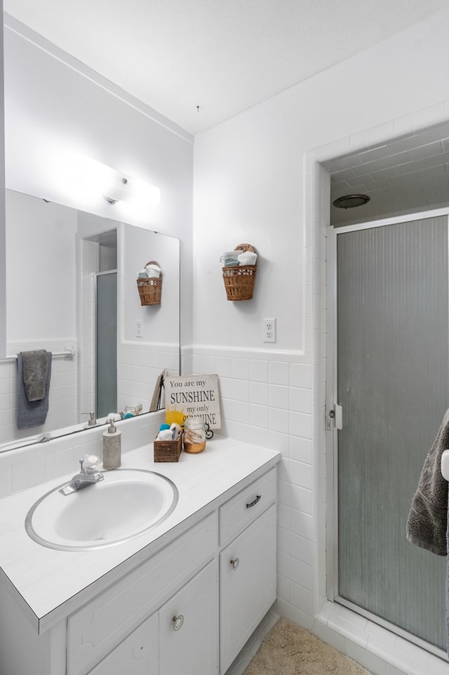 bathroom featuring vanity, a shower with door, and tile walls