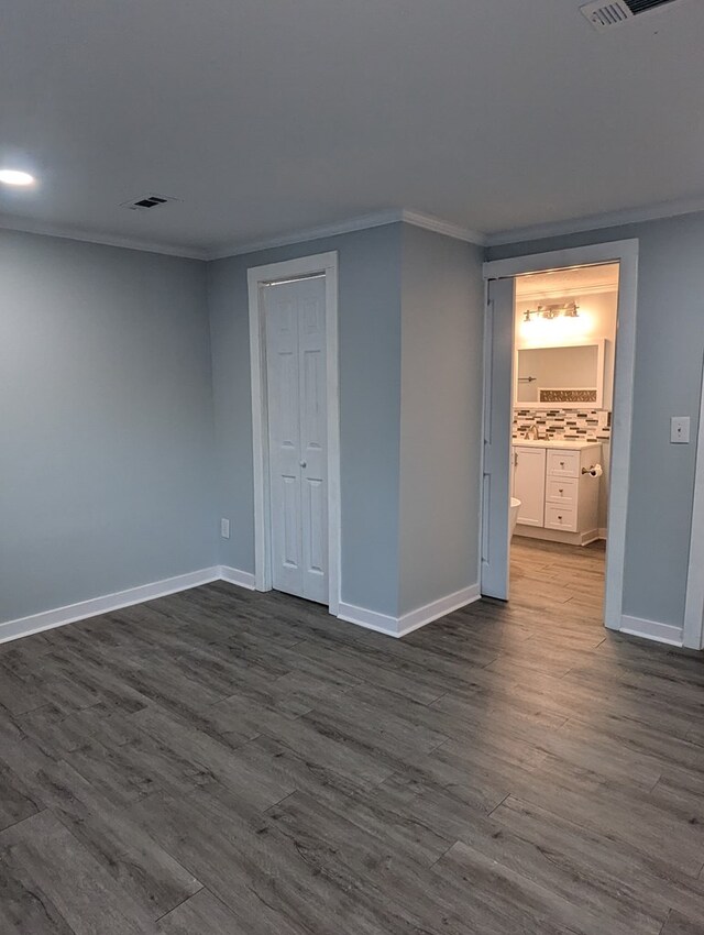 interior space featuring dark wood-style flooring, crown molding, and baseboards