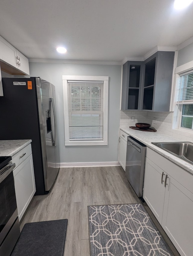 kitchen featuring appliances with stainless steel finishes, light wood-style floors, white cabinets, and tasteful backsplash