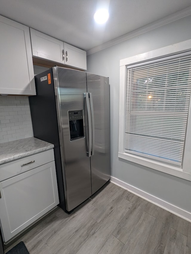 kitchen with crown molding, light wood-style flooring, decorative backsplash, white cabinetry, and stainless steel fridge with ice dispenser