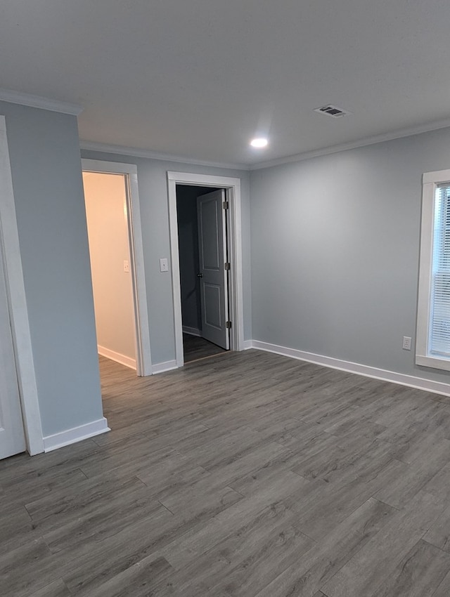 empty room with dark wood-style floors, crown molding, recessed lighting, visible vents, and baseboards