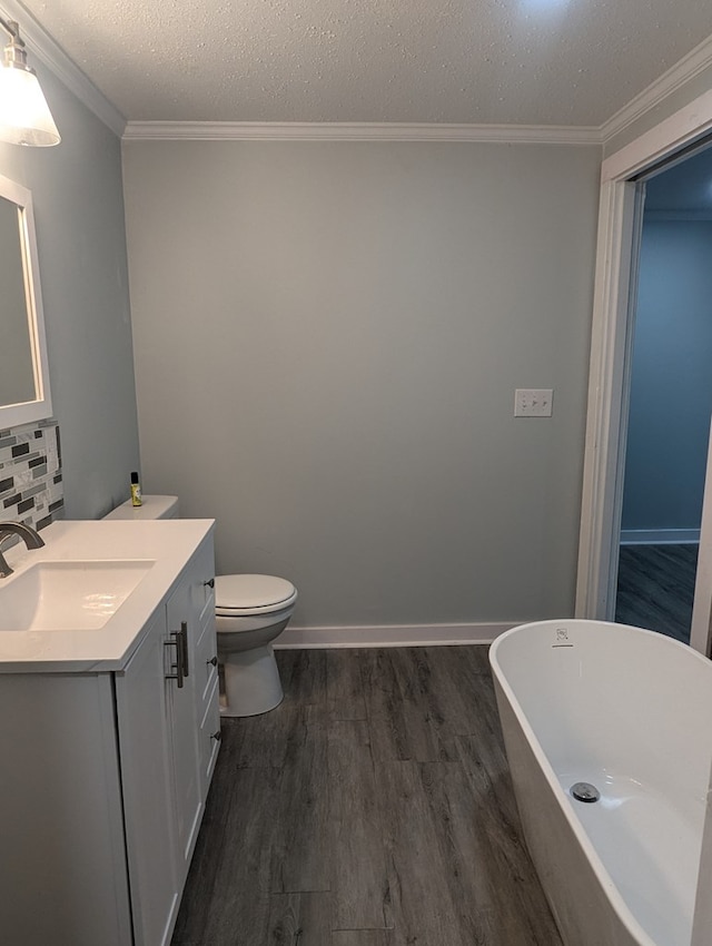 bathroom with vanity, wood finished floors, a textured ceiling, crown molding, and a freestanding bath