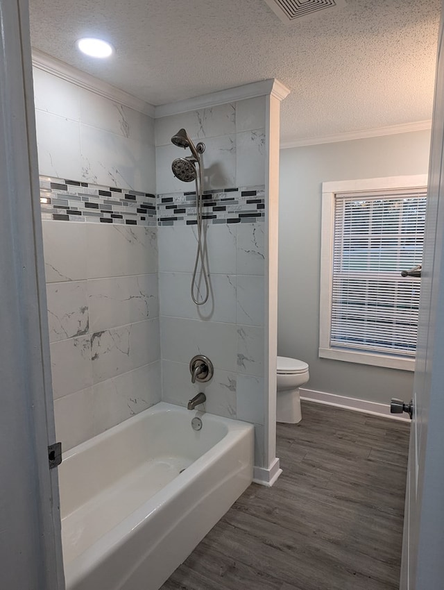 bathroom with a textured ceiling, toilet, wood finished floors, bathing tub / shower combination, and crown molding