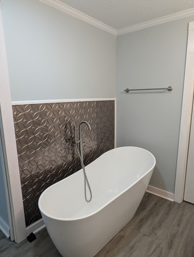 bathroom featuring a freestanding tub, crown molding, and wood finished floors