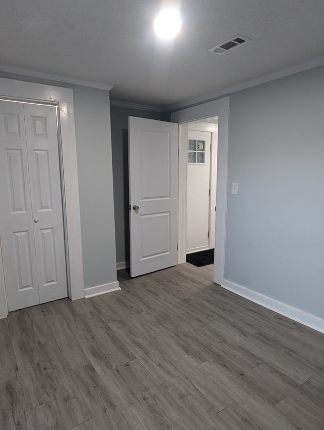 finished below grade area with baseboards, visible vents, crown molding, and wood finished floors