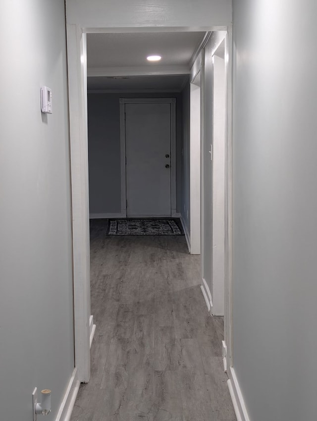 corridor featuring baseboards and wood finished floors