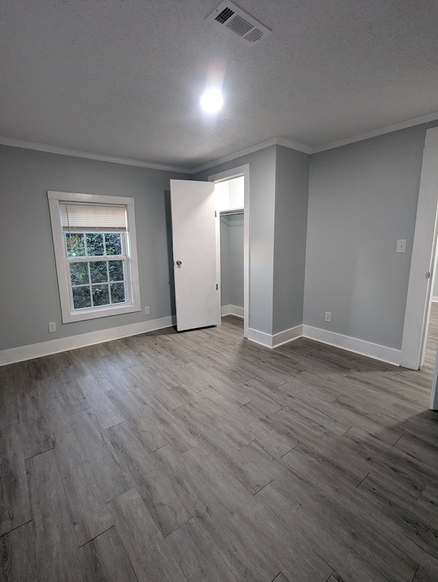 unfurnished room featuring dark wood-style floors, crown molding, visible vents, a textured ceiling, and baseboards