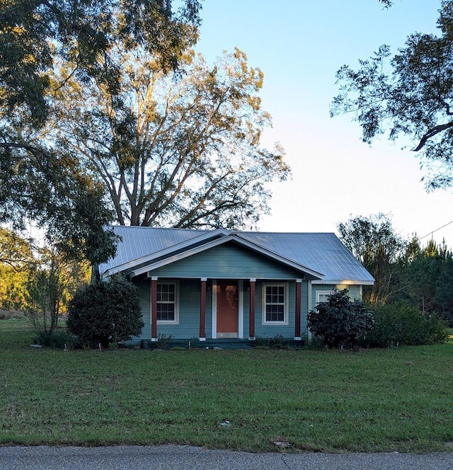 view of front of home with metal roof and a front lawn