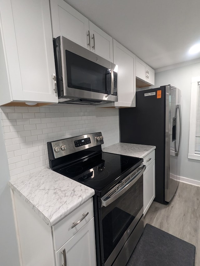 kitchen featuring stainless steel appliances, light countertops, light wood-style floors, and backsplash