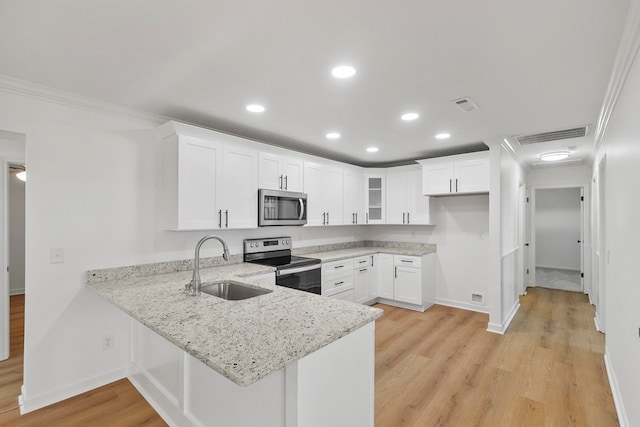 kitchen featuring visible vents, a peninsula, a sink, ornamental molding, and stainless steel appliances