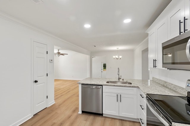 kitchen with light stone countertops, appliances with stainless steel finishes, a peninsula, white cabinets, and a sink