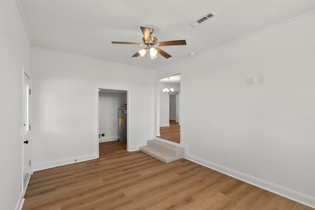 unfurnished room featuring water heater, visible vents, crown molding, and light wood-style floors