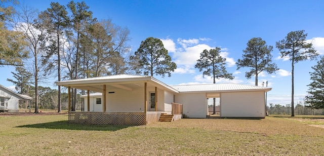 back of property with metal roof and a lawn