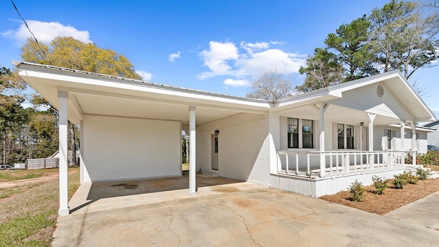 view of front of home featuring metal roof, an attached carport, a porch, and concrete driveway