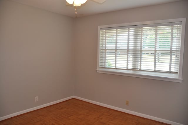 empty room featuring parquet flooring, plenty of natural light, and ceiling fan