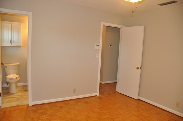 unfurnished bedroom featuring light parquet flooring and ensuite bath