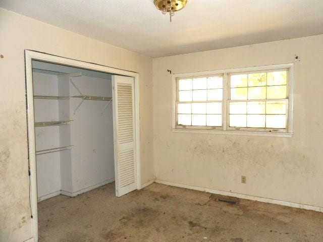 unfurnished bedroom featuring concrete floors and a closet