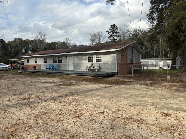 view of front of home with brick siding, fence, and a wooden deck