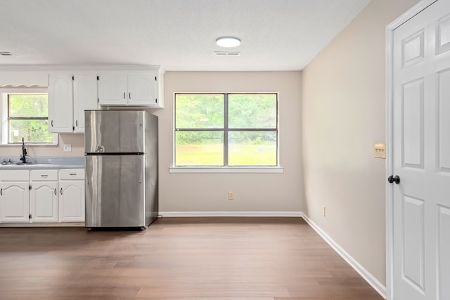 212 Johanna Dr, Ozark, AL 36360 - kitchen with freestanding refrigerator, wood finished floors, white cabinets, and light countertops