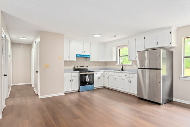 212 Johanna Dr, Ozark, AL 36360 - kitchen with stainless steel appliances, under cabinet range hood, wood finished floors, white cabinetry, and light countertops