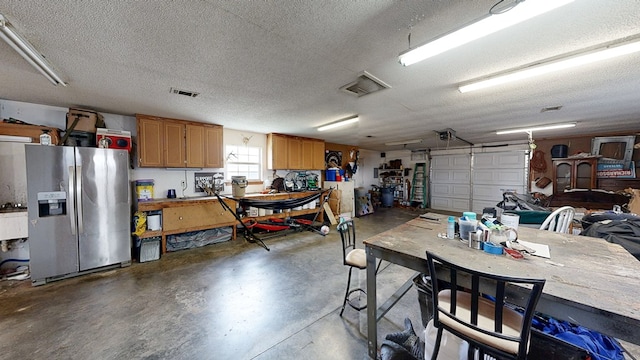 119 Willow Oaks Dr, Headland, AL 36345 - garage featuring a workshop area, visible vents, stainless steel refrigerator with ice dispenser, and a garage door opener