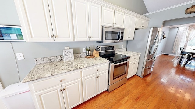 119 Willow Oaks Dr, Headland, AL 36345 - kitchen with lofted ceiling, appliances with stainless steel finishes, crown molding, white cabinets, and light wood-type flooring