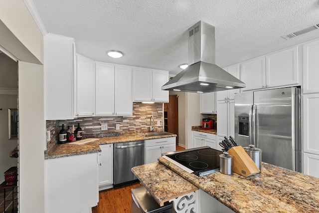 kitchen featuring wood finished floors, visible vents, island exhaust hood, a sink, and stainless steel appliances