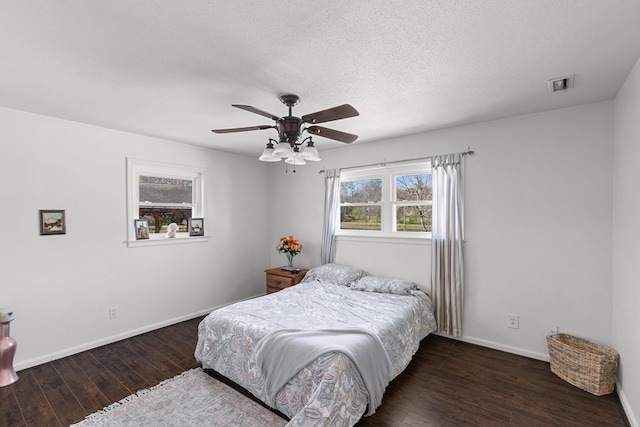 bedroom with visible vents, a textured ceiling, baseboards, and hardwood / wood-style flooring