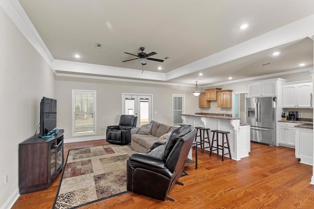 living area featuring light wood-style flooring, a tray ceiling, crown molding, french doors, and recessed lighting