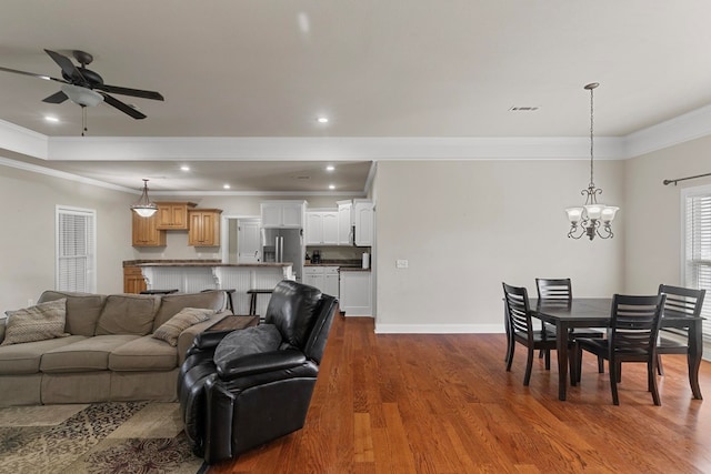 living area with baseboards, ornamental molding, wood finished floors, ceiling fan with notable chandelier, and recessed lighting