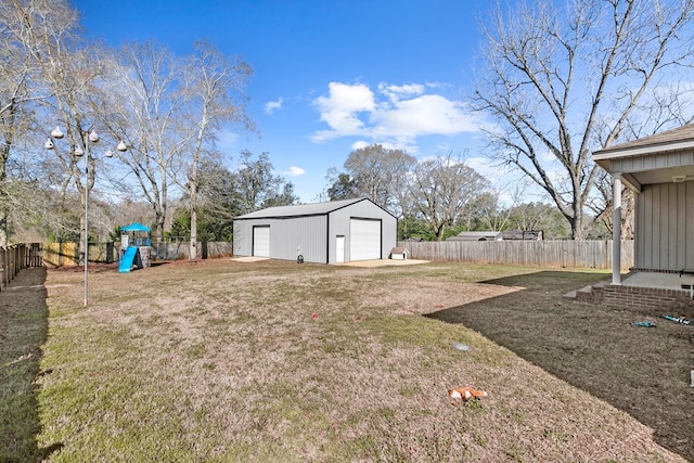 view of yard featuring an outbuilding, a playground, a detached garage, and a fenced backyard