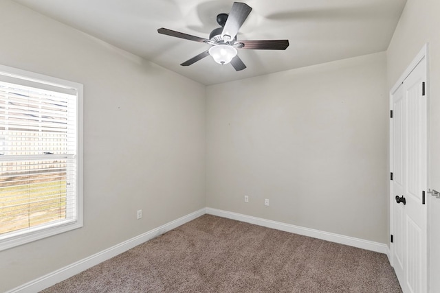 carpeted spare room featuring ceiling fan and baseboards