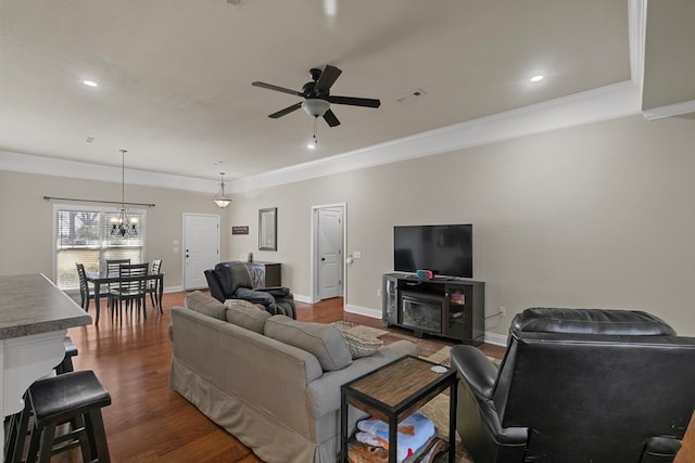 living room featuring baseboards, visible vents, dark wood-style flooring, crown molding, and ceiling fan with notable chandelier