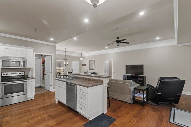 kitchen featuring pendant lighting, dark countertops, appliances with stainless steel finishes, white cabinets, and a sink