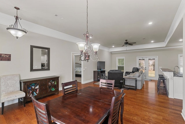 dining area with a tray ceiling, dark wood-style flooring, recessed lighting, ornamental molding, and baseboards