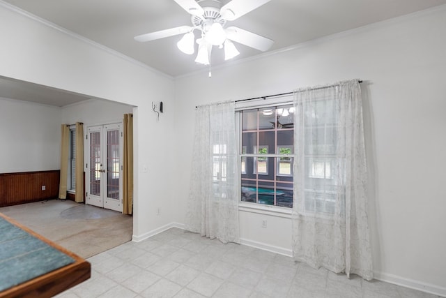 unfurnished room with french doors, crown molding, ceiling fan, and wooden walls