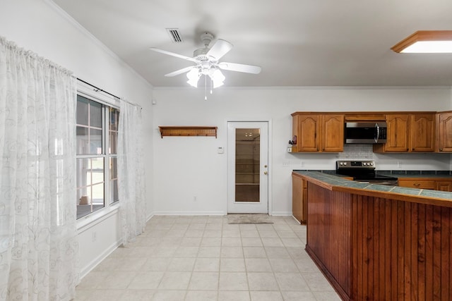 kitchen with crown molding, ceiling fan, appliances with stainless steel finishes, tasteful backsplash, and tile counters