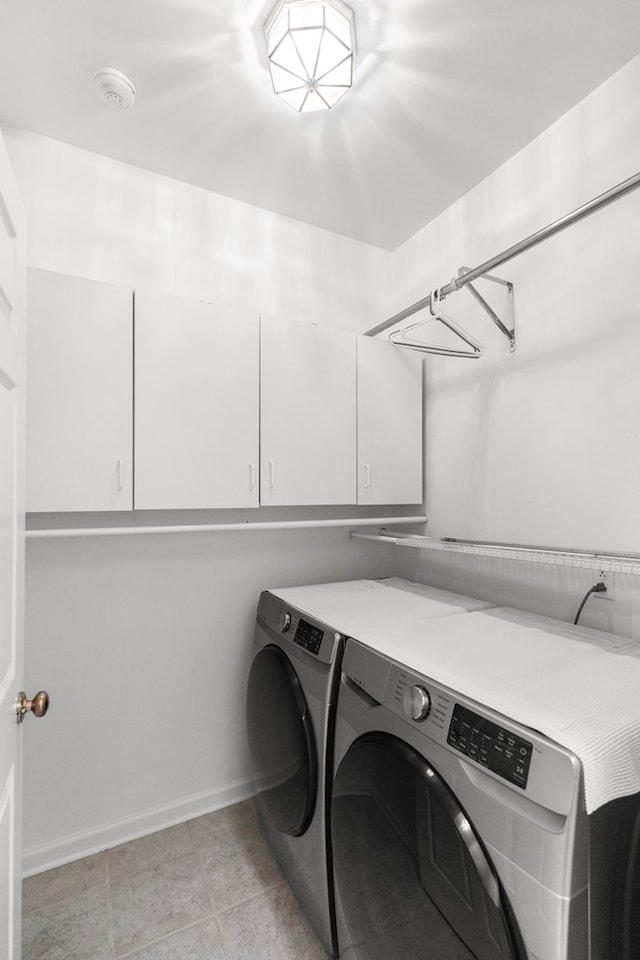 clothes washing area with cabinets and washing machine and dryer