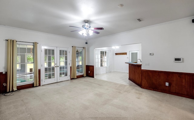 unfurnished living room with crown molding, french doors, and a healthy amount of sunlight