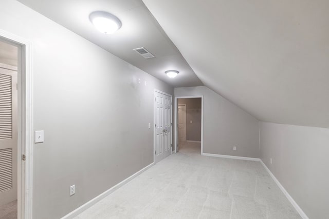 additional living space with light colored carpet and vaulted ceiling