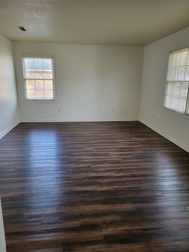 unfurnished room with dark hardwood / wood-style floors and a textured ceiling